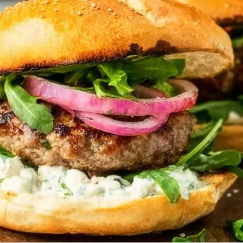 Close-up of garlic smash burgers with melted cheese and fresh toppings.