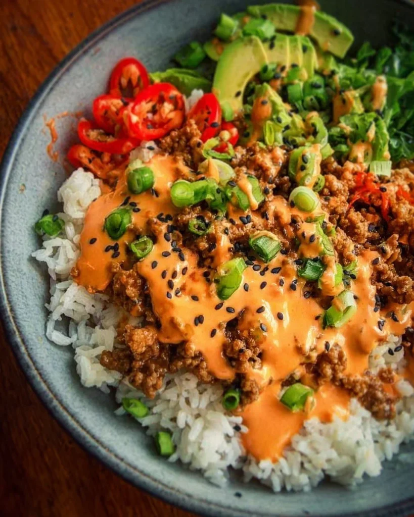 Ground turkey rice bowls with Bang Bang Sauce garnished with fresh vegetables