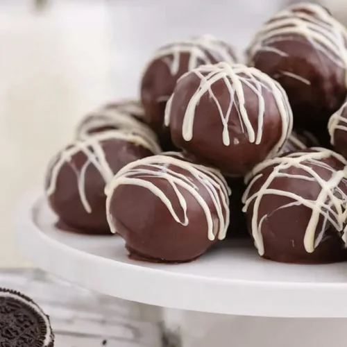 A white plate filled with perfectly round Oreo cream cheese balls.