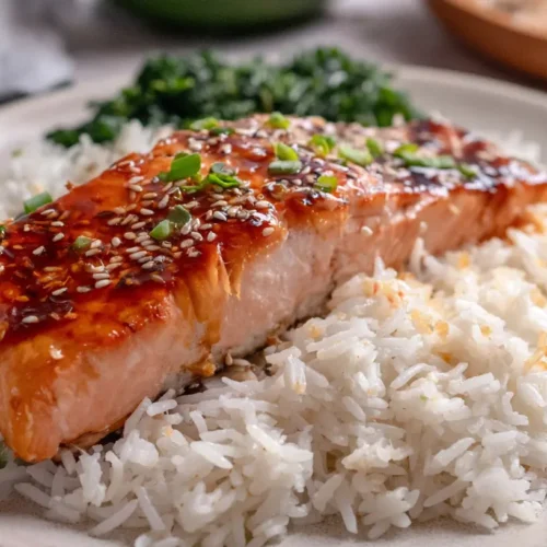 A perfectly cooked salmon fillet next to fluffy white rice.