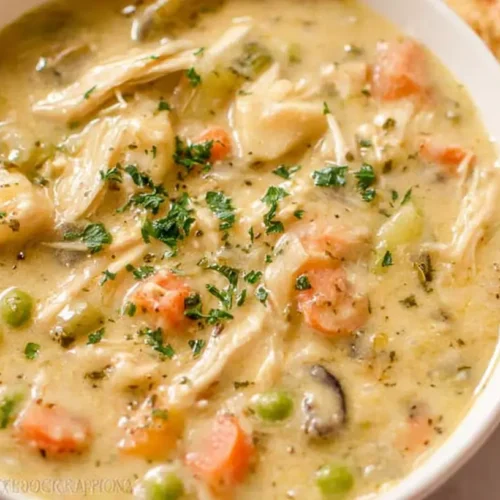 A steaming bowl of chicken pot pie soup, rich with vegetables and tender chicken.