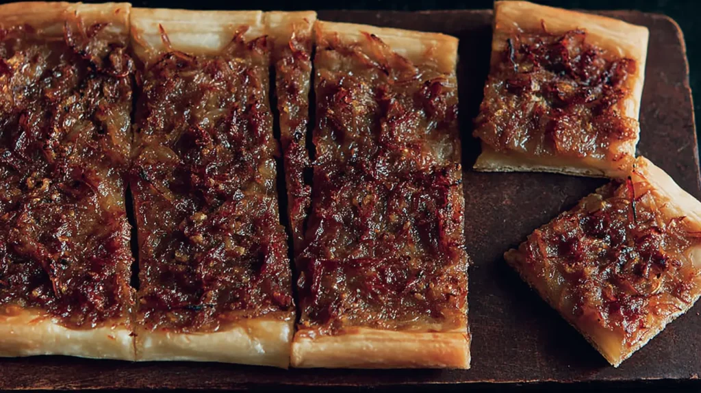 A freshly baked onion tart, sliced and ready to serve.