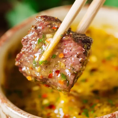 A small bowl of creamy cowboy butter dipping sauce on a rustic wooden surface.