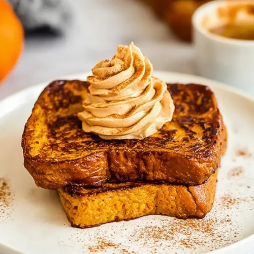 Plated Pumpkin French Toast drizzled with maple syrup and powdered sugar.