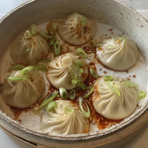 A plate of savory soup dumplings, fresh from the steamer