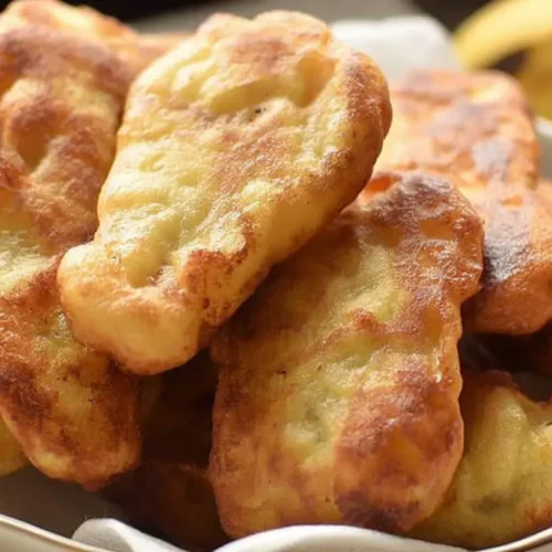 A plate of golden-brown banana fritters, fresh and hot.