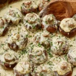 A platter of golden-brown roasted mushrooms, generously stuffed with creamy garlic and herb cheese.