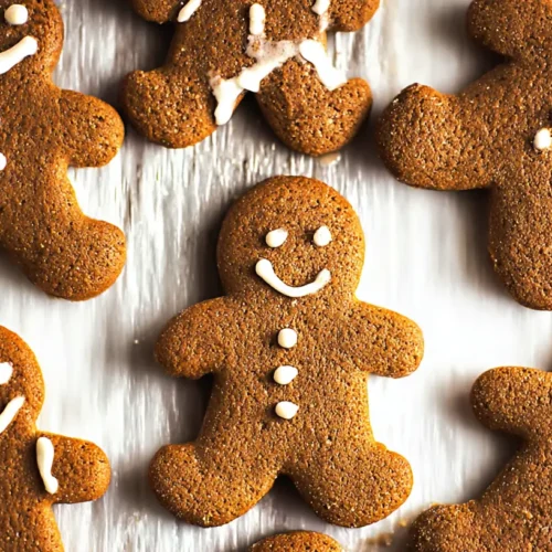 A plate of freshly baked chewy gingerbread man cookies, decorated with white icing smiles.