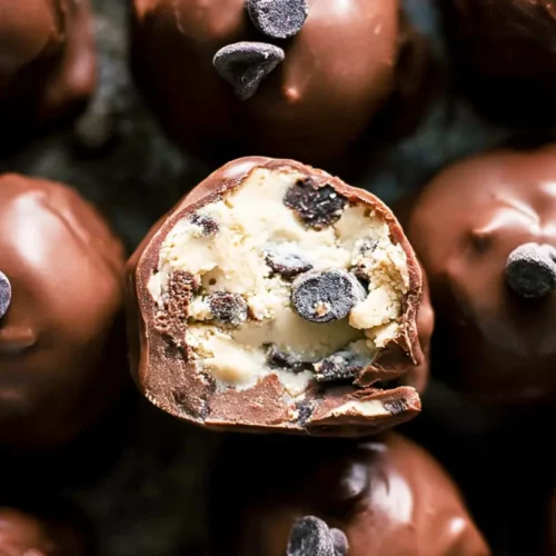 A close-up shot of decadent chocolate chip cookie dough truffles, sprinkled with chocolate shavings.