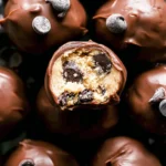Several round chocolate chip cookie dough truffles neatly arranged on a white serving platter.