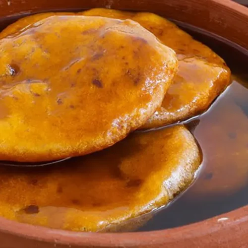 A plate of golden-brown sopaipillas dusted with powdered sugar