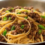 Delicious Mongolian ground beef noodles ready to be served, garnished with fresh scallions.