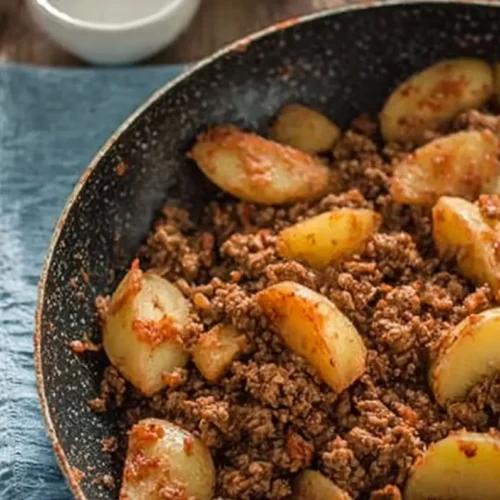 A close-up of a skillet filled with seasoned ground beef and potatoes, ready to be served.