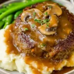 Close-up of Salisbury steak smothered in rich brown gravy.