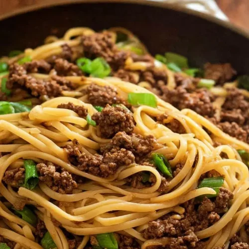 A close-up of Mongolian ground beef noodles in a bowl, showing the savory sauce and tender beef.