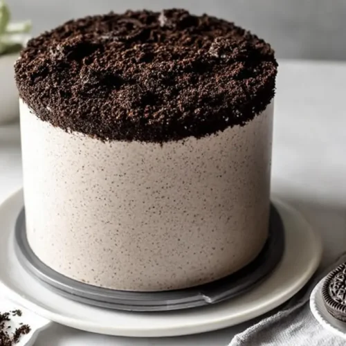 A decadent Oreo cake slice with cookie crumbles and creamy frosting.