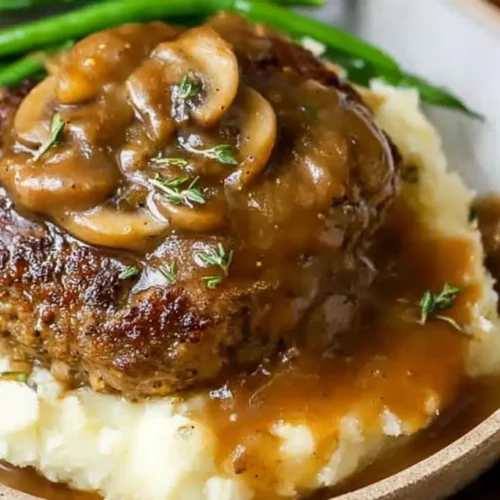 A serving of Salisbury steak and gravy with mashed potatoes.