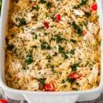 Close-up of a golden-brown French Onion Chicken Orzo Casserole garnished with fresh herbs.