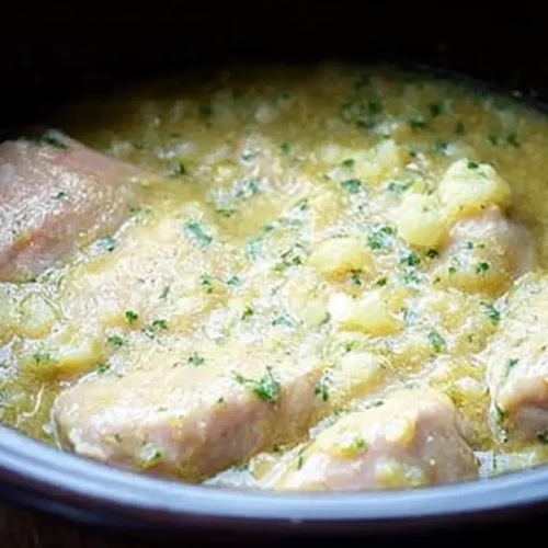 A steaming bowl of slow cooker chicken dumplings, rich with broth and vegetables and chicken.