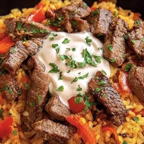 A serving of Steak Queso Rice on a plate, rich with melted cheese and tender steak
