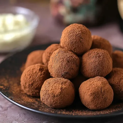 A close-up of several exquisitely crafted Tiramisu Truffles, dusted with cocoa powder.