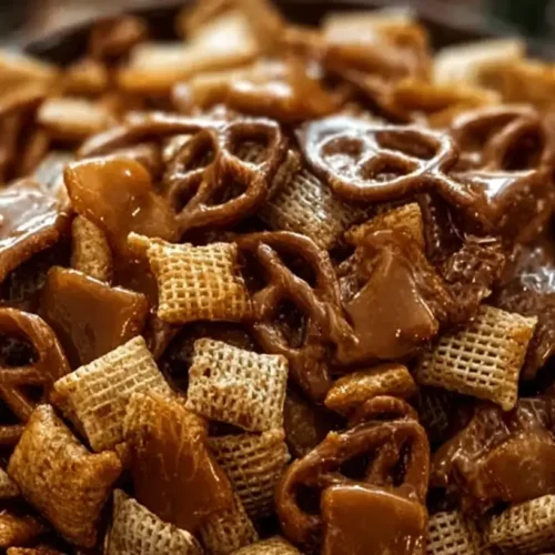 A close-up of a bowl filled with Toffee Chex Mix, featuring golden Chex cereal pieces coated in toffee.