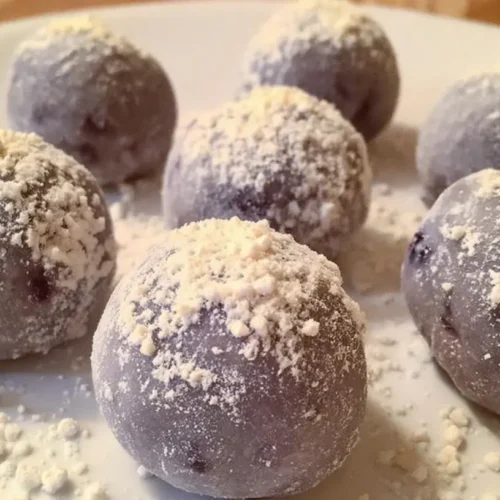 A close-up of white chocolate blueberry truffles arranged on a platter, showcasing their smooth coating.