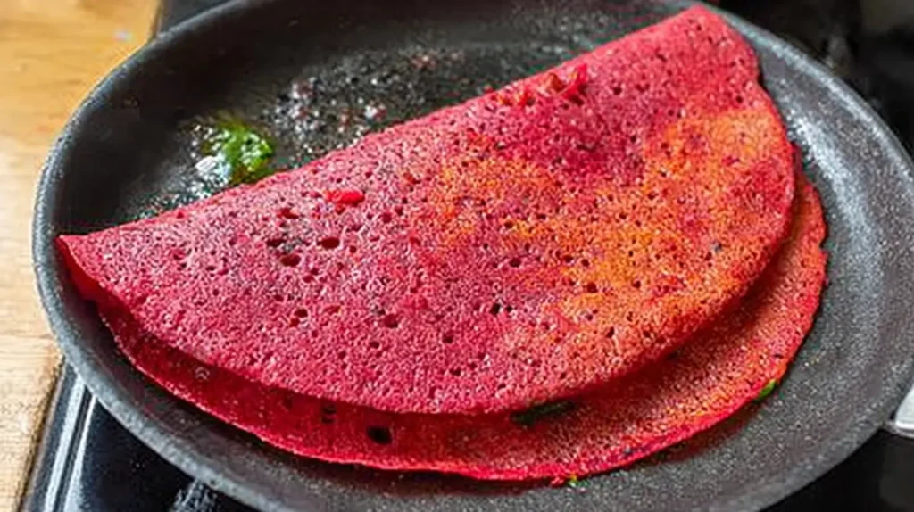 A visually appealing pink beetroot dosa, ready to be enjoyed, highlighting its crispiness.