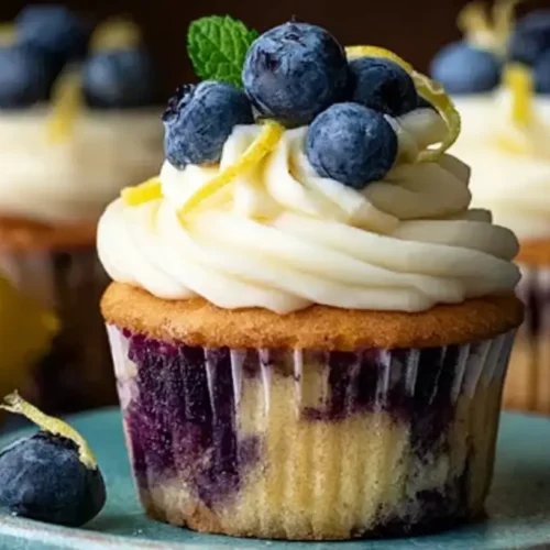 A trio of delicious lemon blueberry cupcakes, topped with swirl frosting and fresh blueberries.