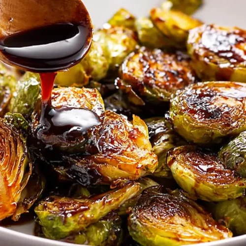 Maple Balsamic Chicken with crispy Brussels sprouts, artfully plated with a sweet glaze.