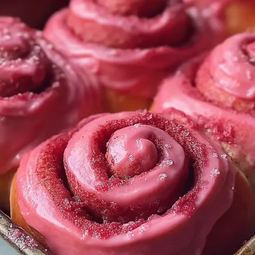 Freshly baked pink velvet cinnamon rolls artfully arranged.