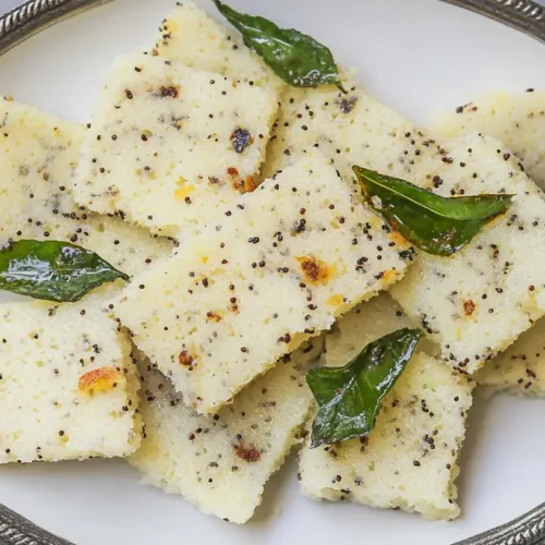 Steamed Rava Dhokla garnished with coriander and mustard seeds
