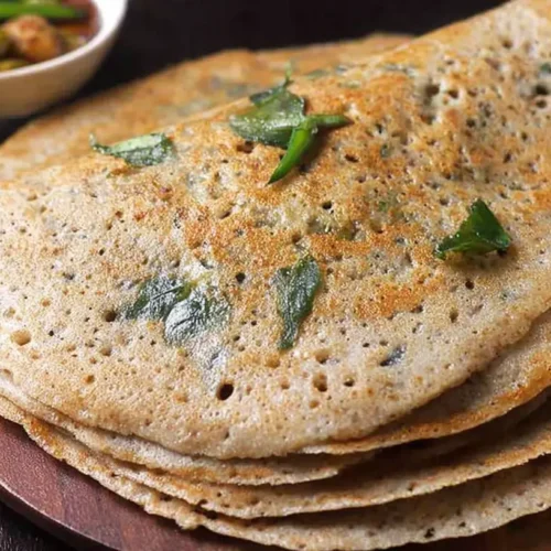 A freshly made wheat dosa, golden brown and perfectly cooked, on a white plate.
