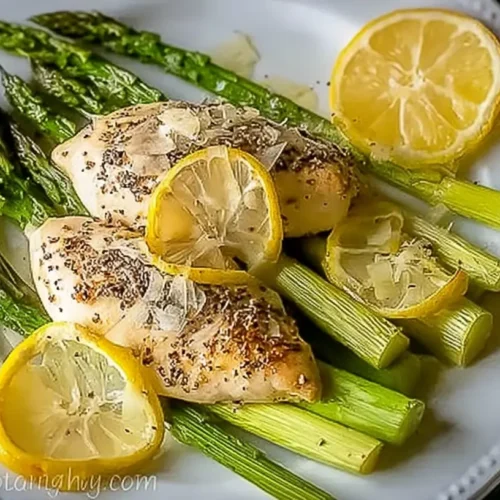 A full sheet pan of lemon pepper chicken and asparagus with crisp edges
