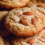 Several chewy almond cookies arranged neatly on parchment paper