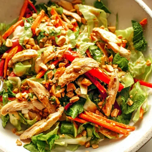 A vibrant Chicken Thai Crunch Salad with shredded cabbage, fresh herbs, and a peanut-lime dressing.