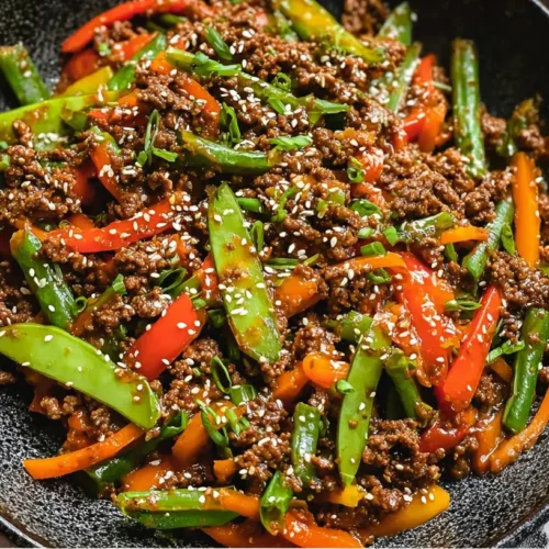 A close-up of ground beef and vegetable stir fry in a wok with colorful vegetables.