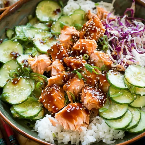 A Sesame Ginger Salmon Bowl with wild rice, sliced cucumbers, and a quick sauce.