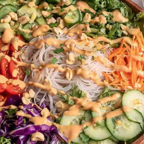 A vibrant spring roll salad featuring crunchy vegetables and creamy peanut dressing.