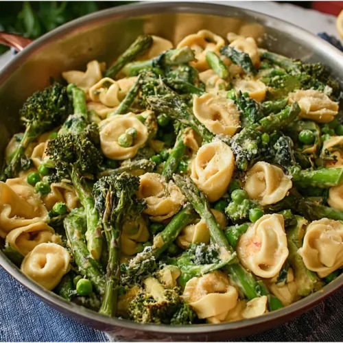 A colorful bowl of Tortellini Primavera, brimming with fresh spring vegetables.