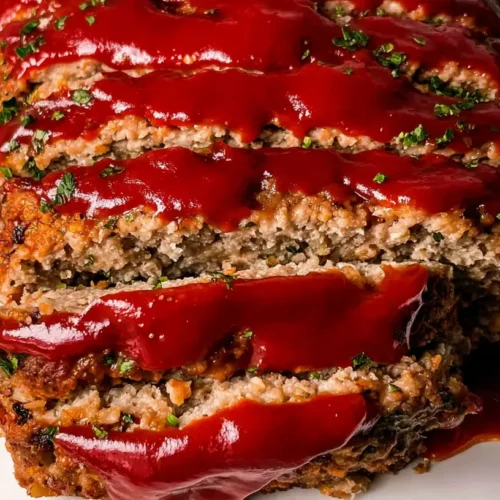 A full comfort food meatloaf dinner with mashed potatoes and green beans on a white plate.