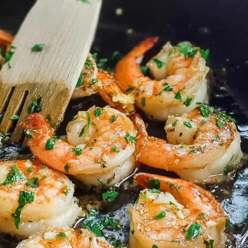A serving of skillet shrimp cooked with fresh lemon slices and herbs.