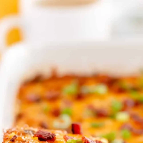 An uncooked breakfast casserole ready to be baked, showing various ingredients layered.
