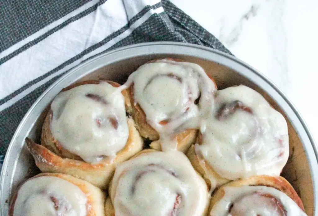 Freshly baked cinnamon rolls generously topped with white cream cheese frosting.