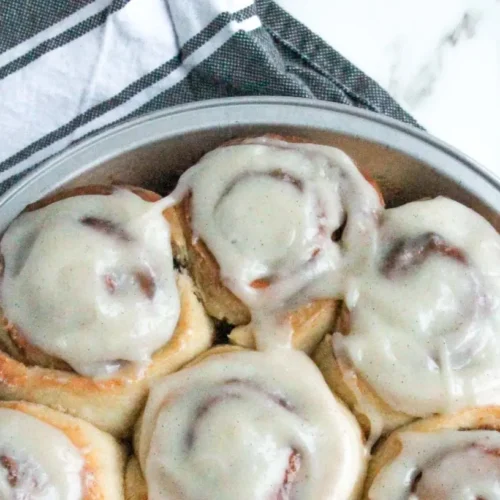 Freshly baked cinnamon rolls generously topped with white cream cheese frosting.