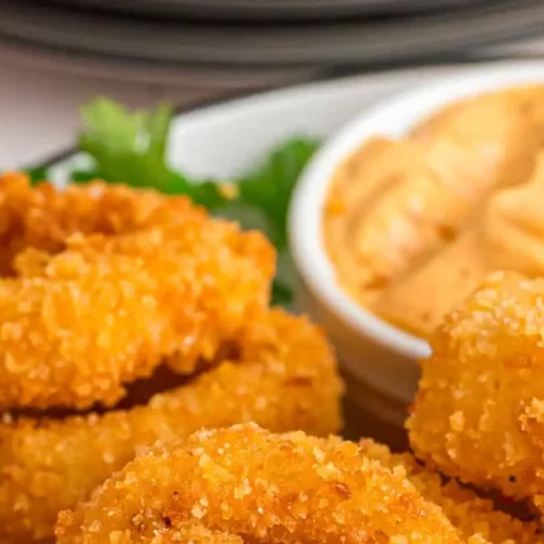 A pile of crispy, golden-brown onion rings, freshly fried.