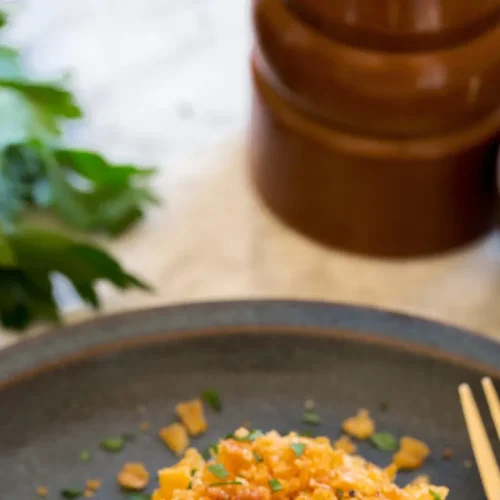 Close-up of a creamy funeral potatoes casserole dish with a golden crust and crunchy topping.