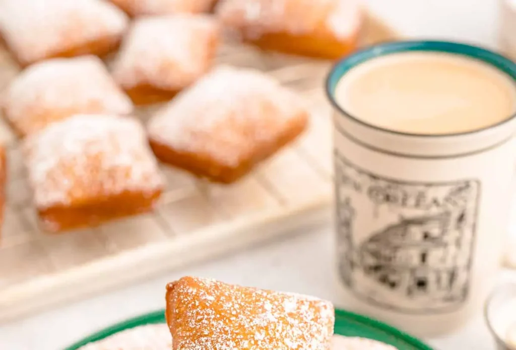 Freshly made New Orleans beignets dusted generously with powdered sugar in a classic setting.