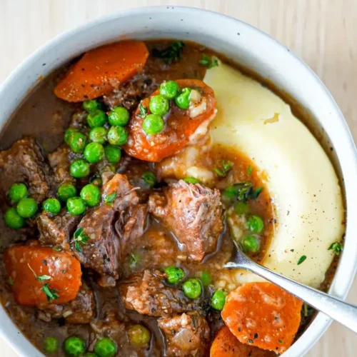 A steaming bowl of slow cooker beef stew garnished with fresh parsley.