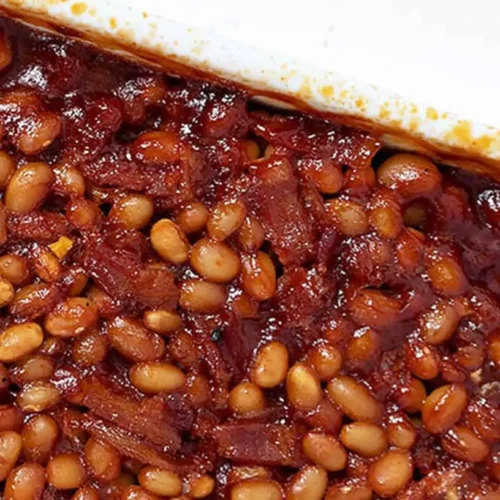 A serving of smoked baked beans with hearty bacon pieces mixed in.